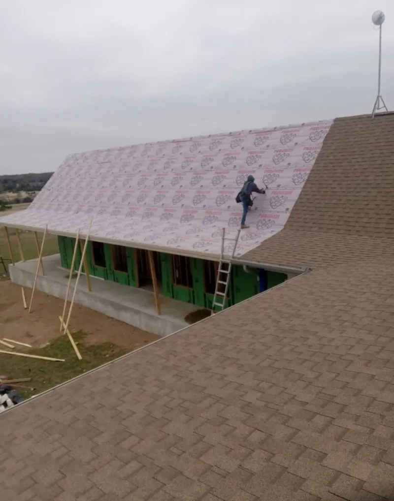 Worker preparing underlayment for a metal roof installation in Shaw Heights